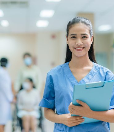 Portrait of Asian female nurse wearing uniform working in hospital with doctor and patient sitting on wheelchair background